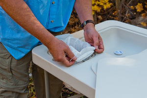 Man demonstrating how to use the refuse hole with easy-snap locking system to easily hold a trash bag in place.