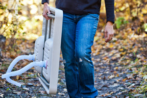 Woman demonstrating the simple portability of the Ultimate Outdoor Work Station.